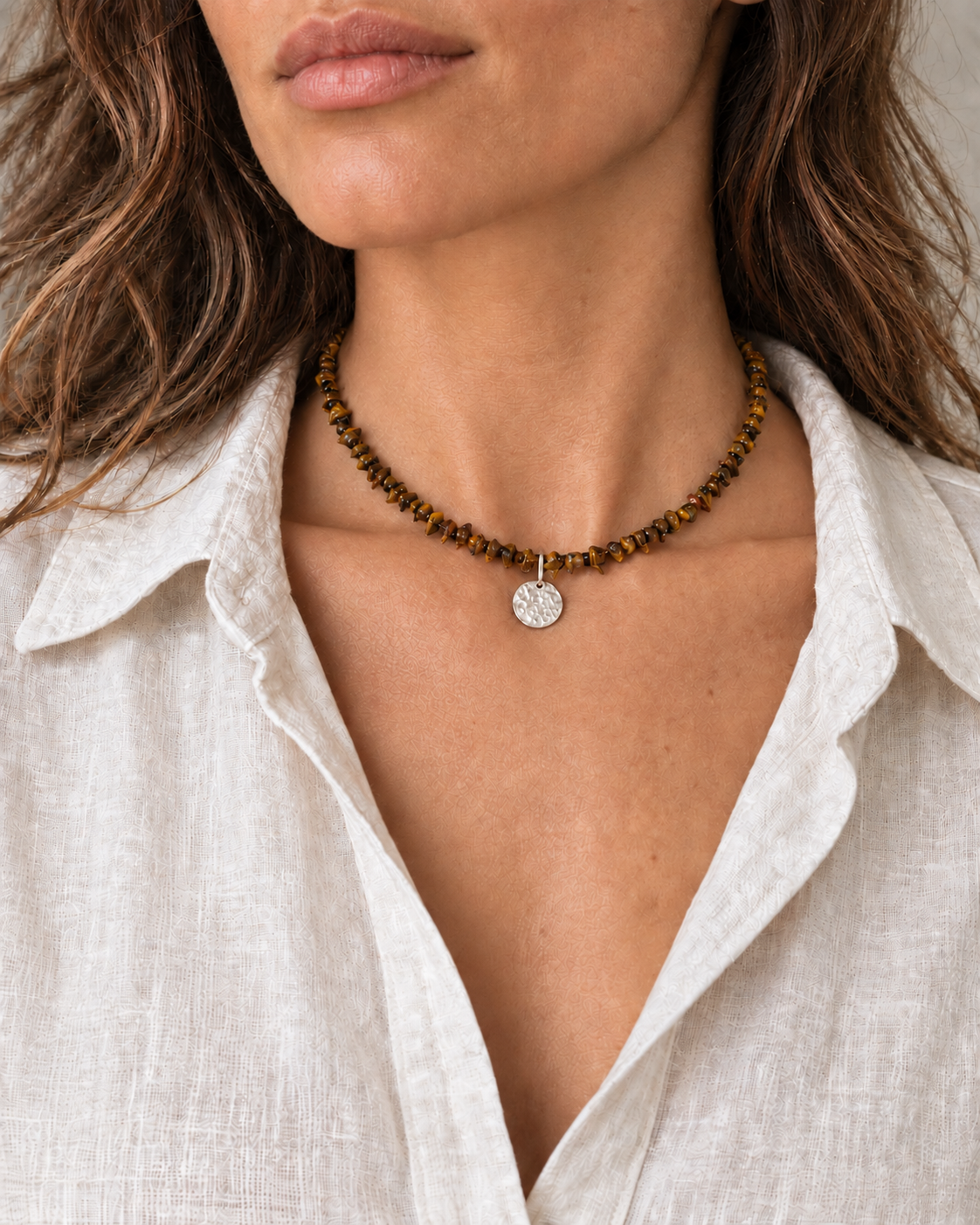 Tiger’s eye chipstone necklace with a hammered silver pendant worn with a linen shirt